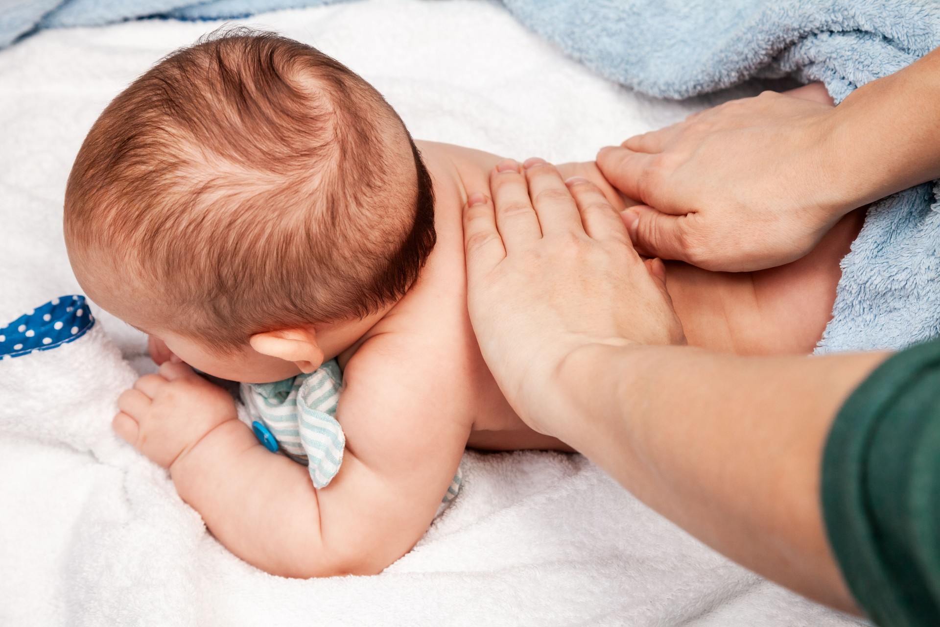 Little baby receiving chiropractic treatment of her back at home