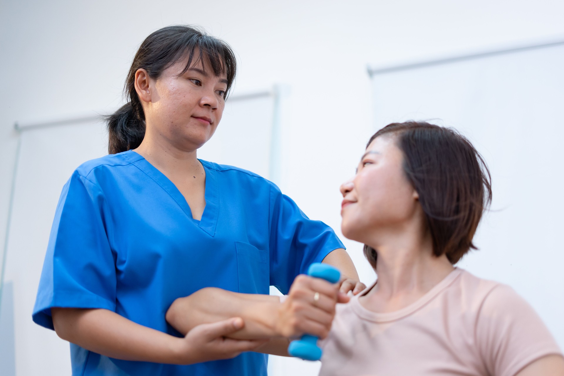 Physical therapist assists patient with arm exercises